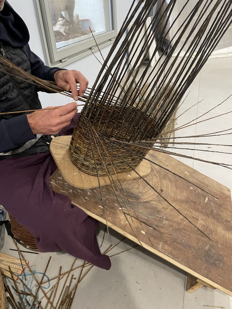 Artisan vannier en train de réaliser un panier en osier 